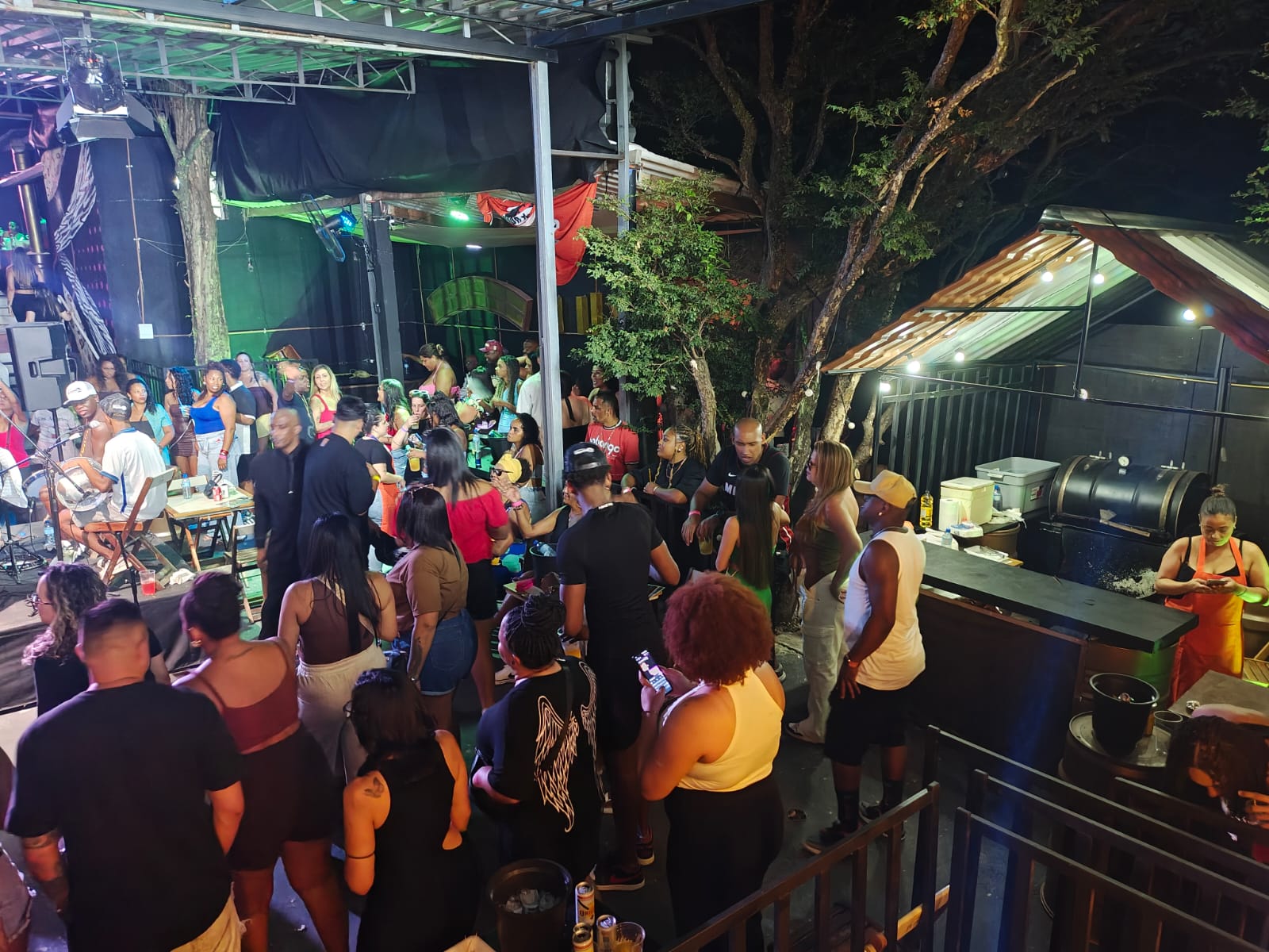 Área de churrasco arborizada com público da casa